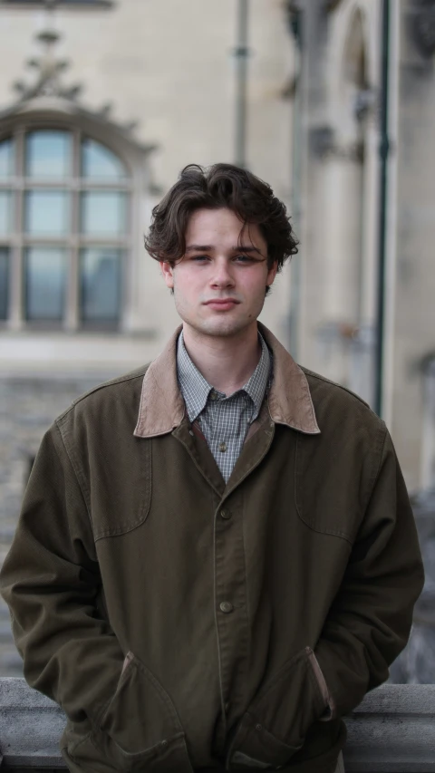 a young man in an overcoat is standing by some steps