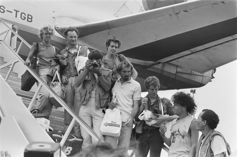 black and white pograph of group of people getting on an airplane