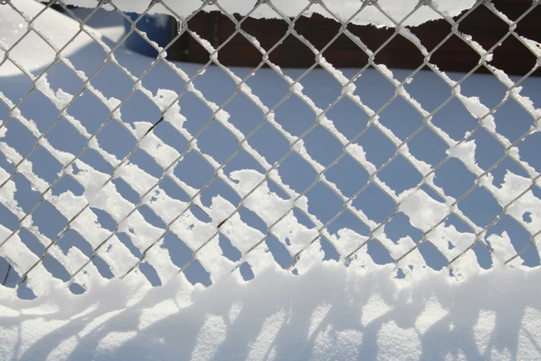 a chain link fence covered in snow next to a house