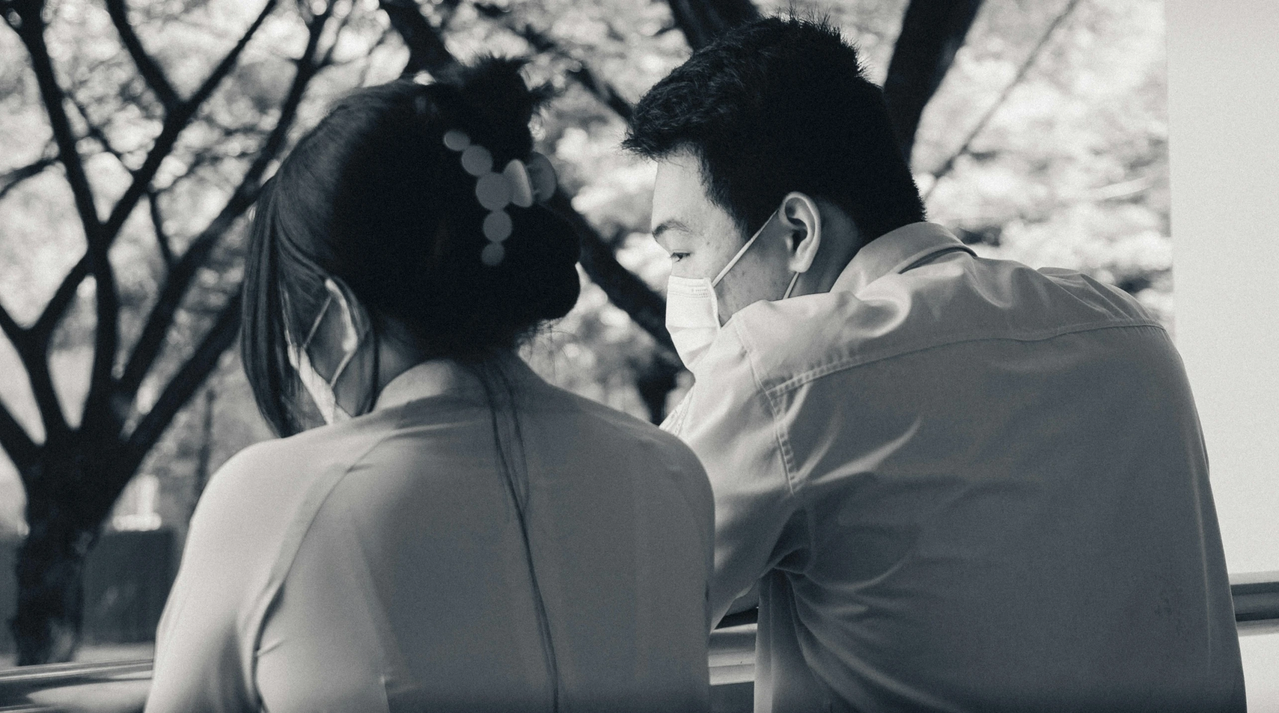 man and woman sitting on park bench facing each other