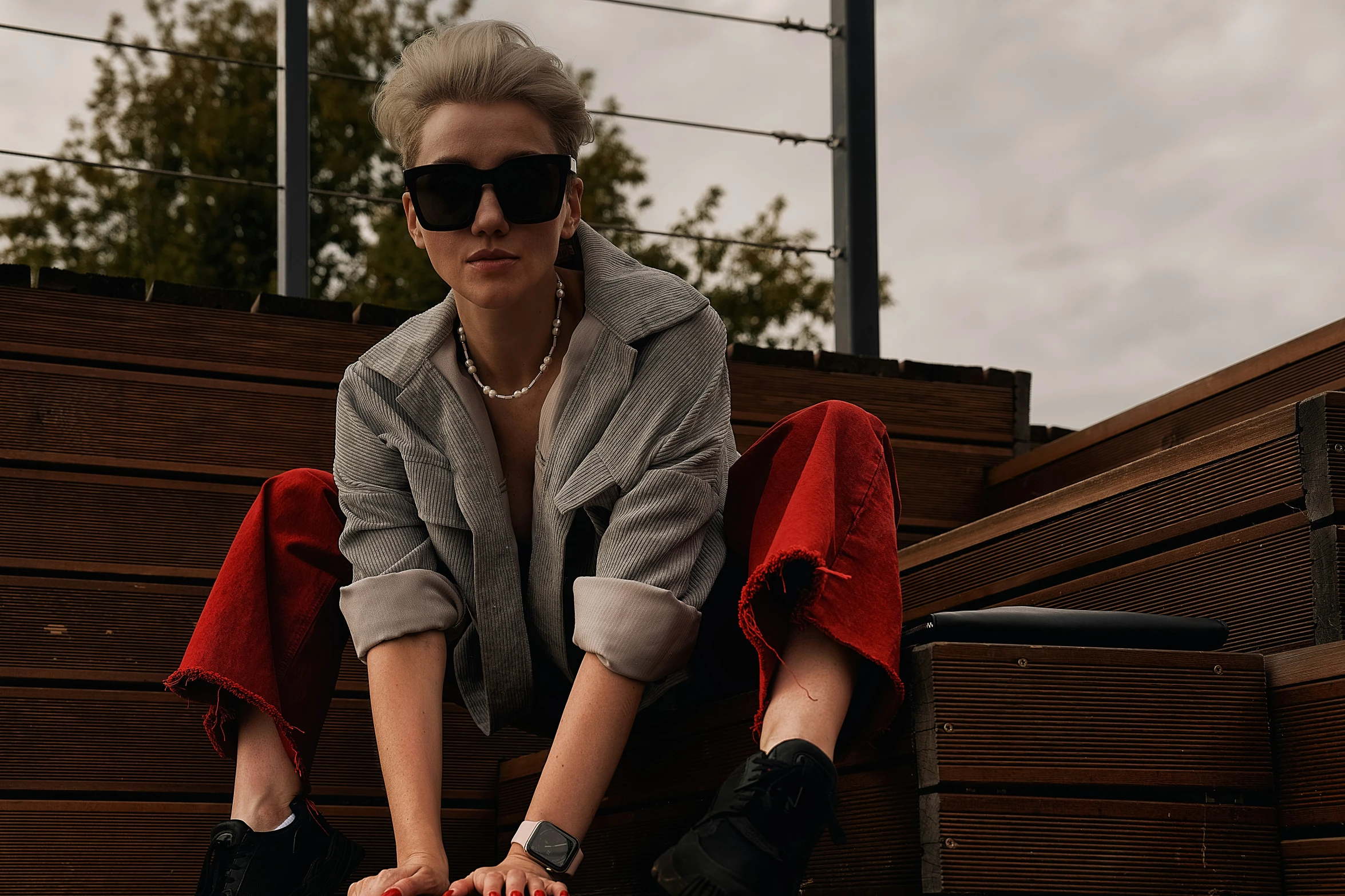 a woman sits on a bench wearing glasses