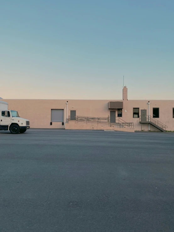 a white truck is parked near a large beige building