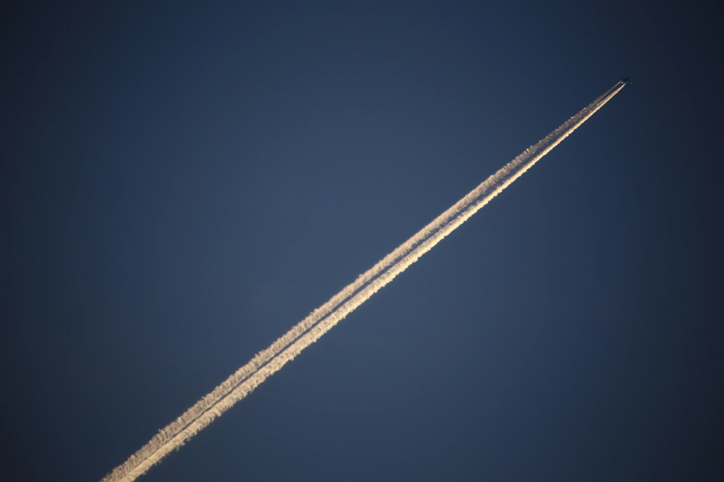 the contrail is flying through the blue sky