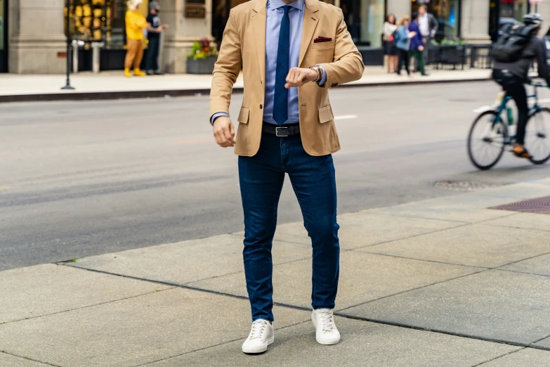 a man in a jacket and tie standing on a city street