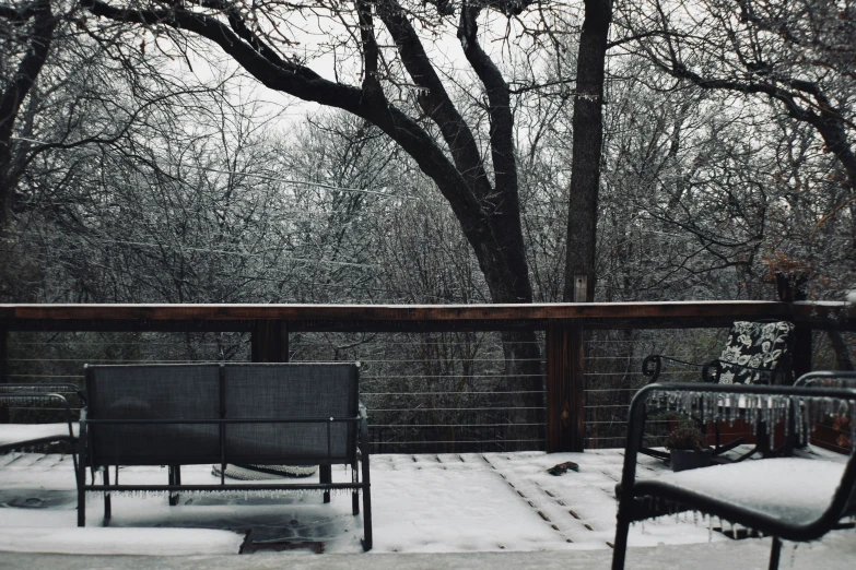 an outdoor patio deck covered with snow next to trees