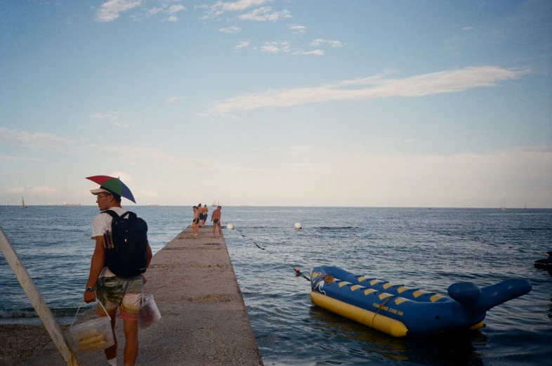 a man standing at the end of a pier with an inflatable boat