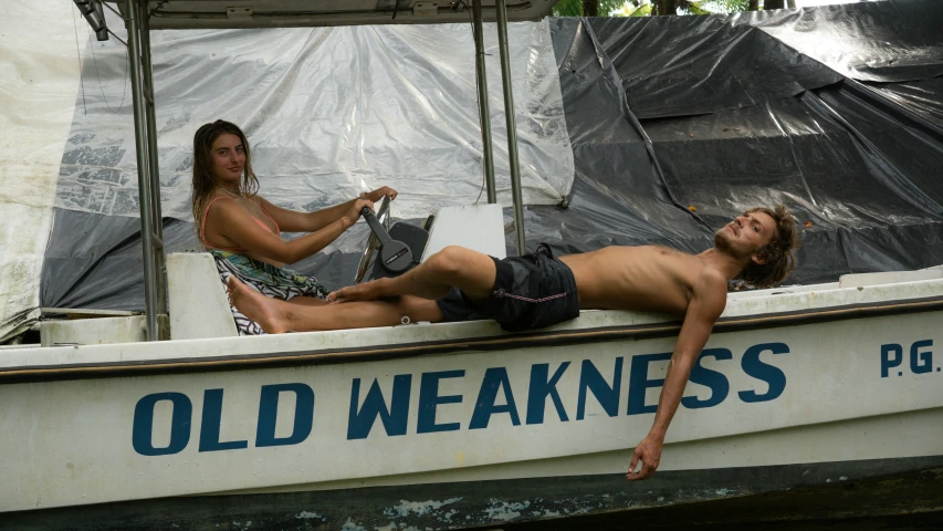 two young men are sitting on the back of a boat