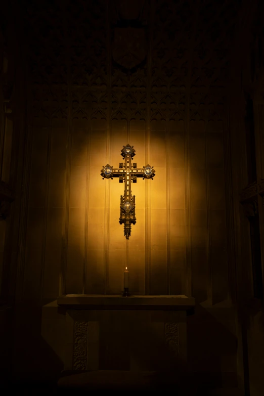 a yellow cross lit on the side of a wooden wall