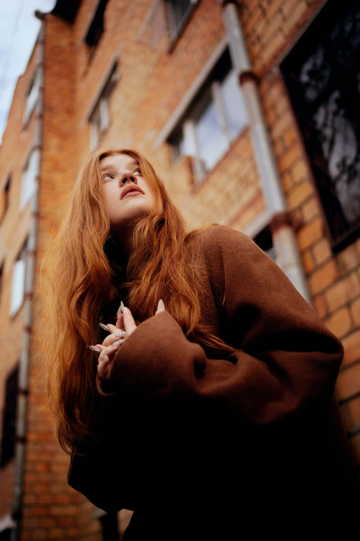 the woman is standing outside next to a brick building