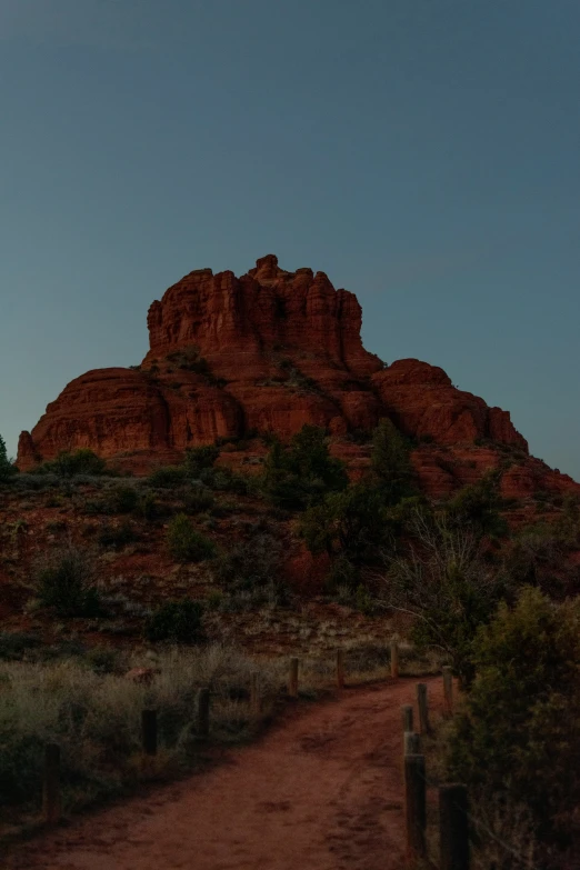 a dirt path to a red cliff at dusk