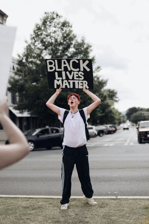 there is a man holding a sign on the sidewalk