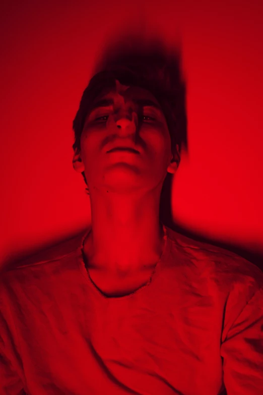 a man staring upward at the camera with red light on his