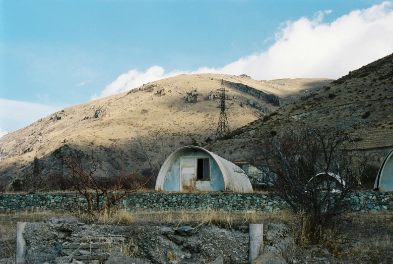 an old stone house that sits next to the mountains