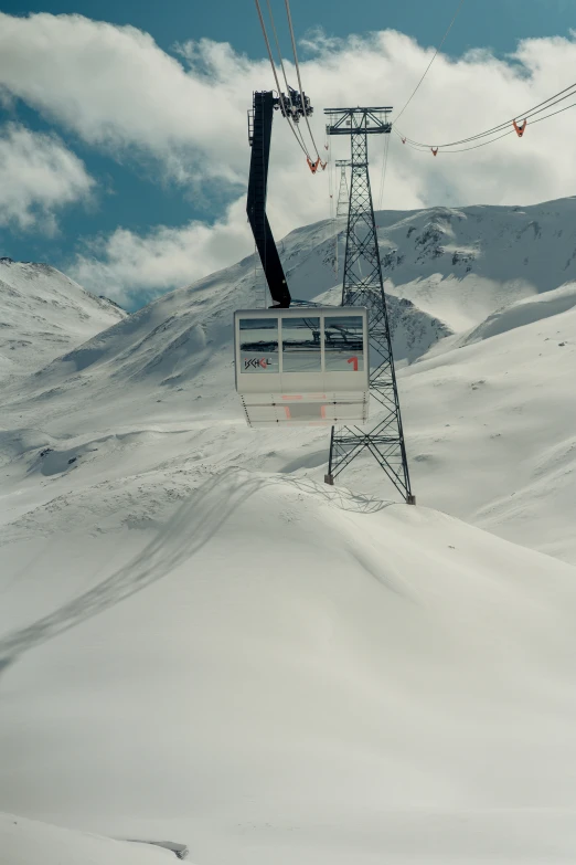 a ski lift suspended over snow covered mountains