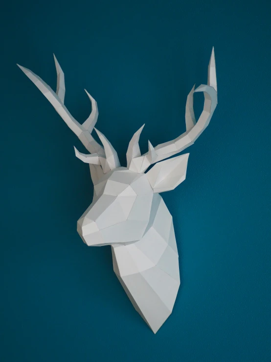 a papercraft deer head on a blue surface