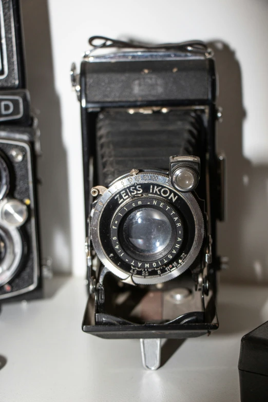 two old fashioned cameras with no faces are seen