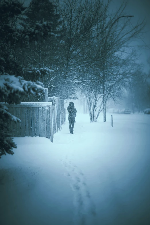 a person in the snow with their footprints up against a fence