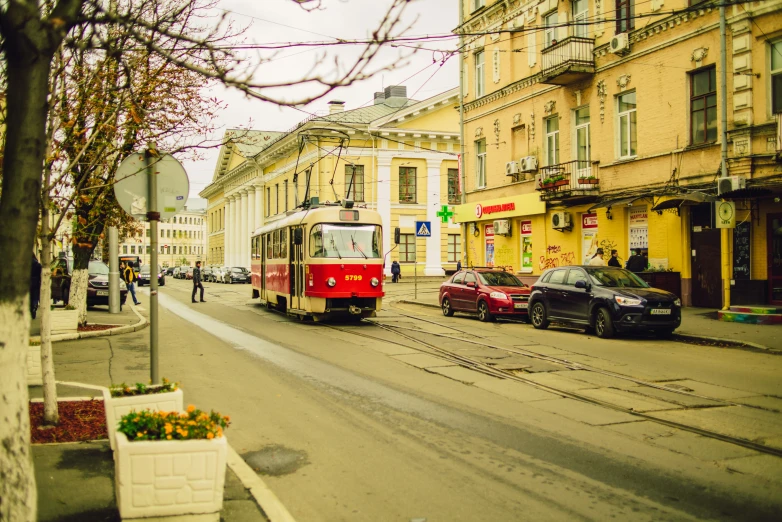 a red and white trolley and some cars on a street