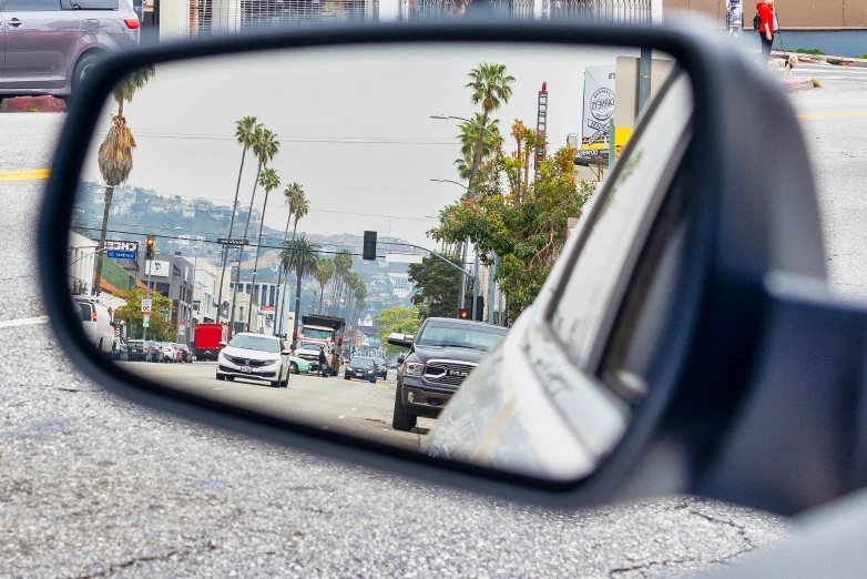 side view mirror reflecting cars on the road