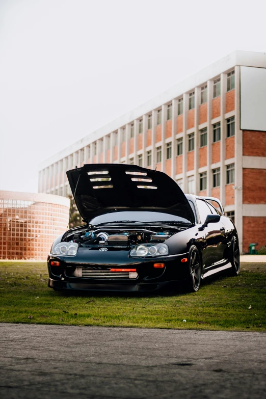 a sports car with the hood open on the grass