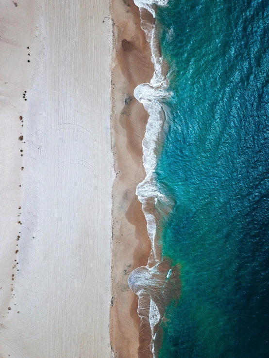 an aerial view of a sandy beach with a surfboard