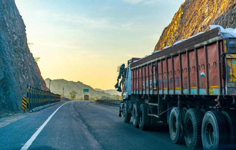 the yellow and red dump truck drives down the hill side