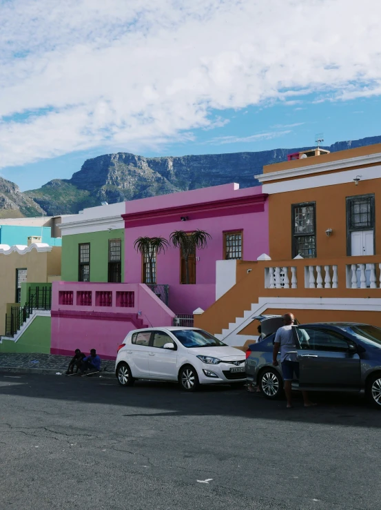 two cars parked in front of colorful houses