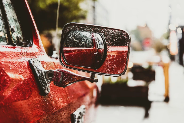 a side view mirror on a car that is parked in front of a building