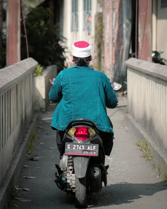 man riding on motor scooter in front of a fence