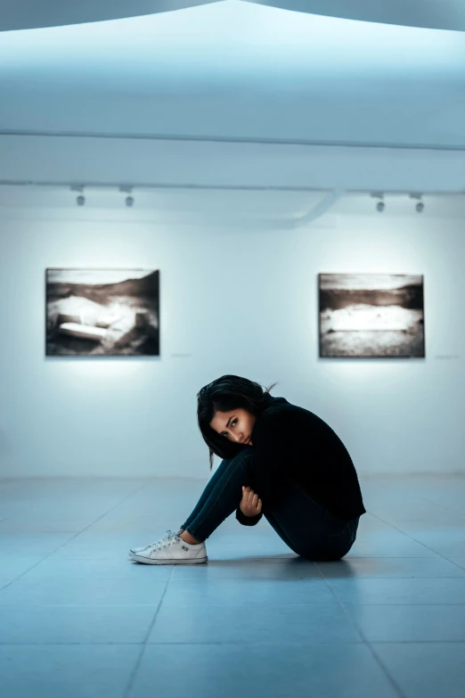 a  sitting in front of a white wall with paintings on the walls