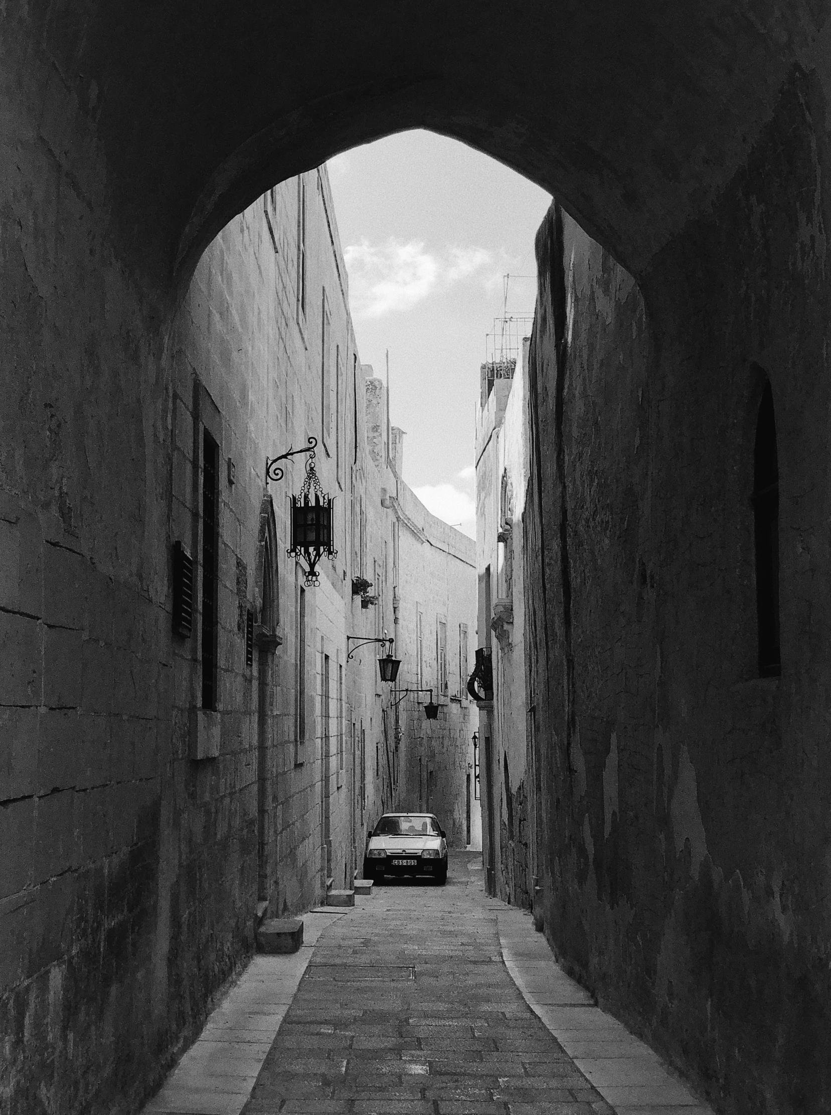 a dark and narrow alleyway has a white car parked near the end