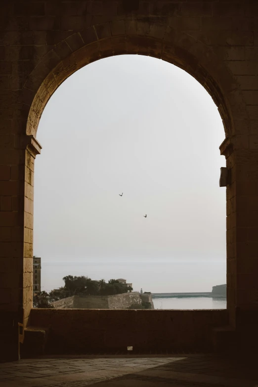 a stone structure with a large window overlooking the ocean