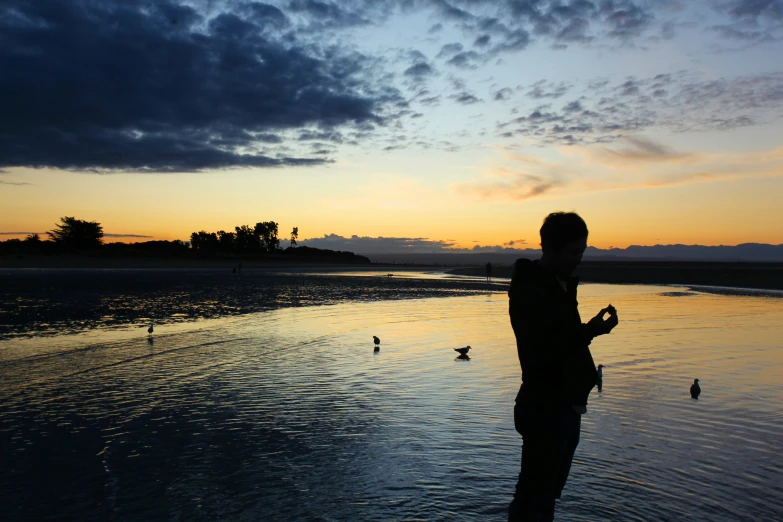 a young man is standing in water as the sun sets