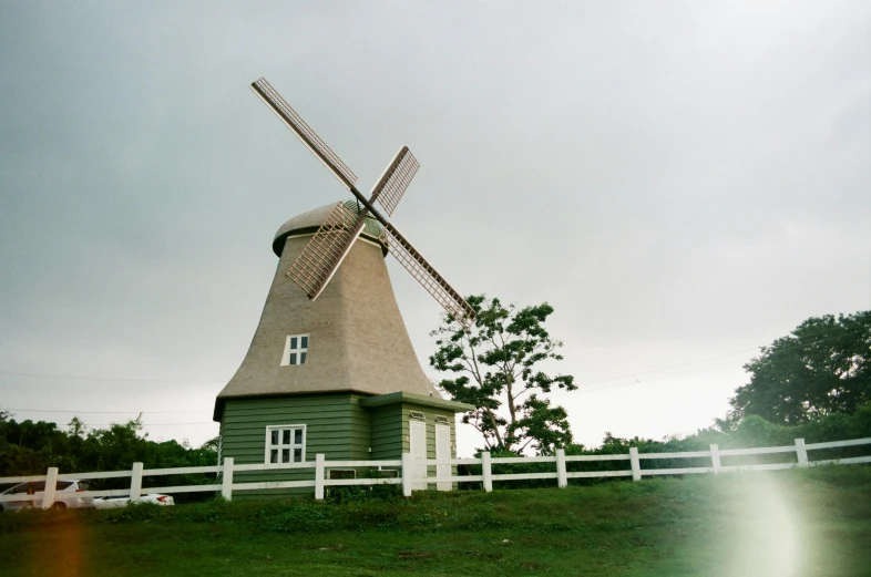 a windmill with white rails on top of it near some trees