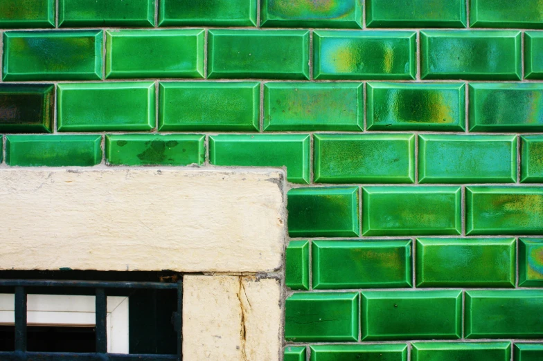 a green tiled wall has a window in it