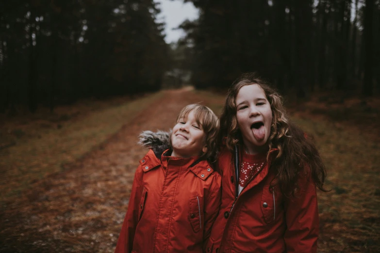 two children are standing in the woods, their noses open