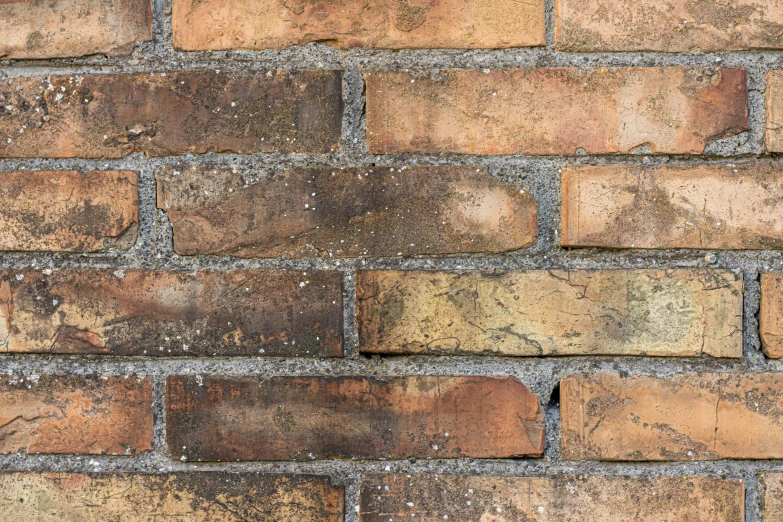 a closeup of an old brick wall made of brown, yellow and black bricks