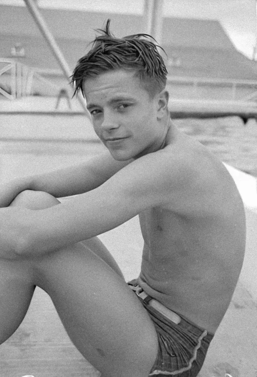 a young man is sitting in the sand