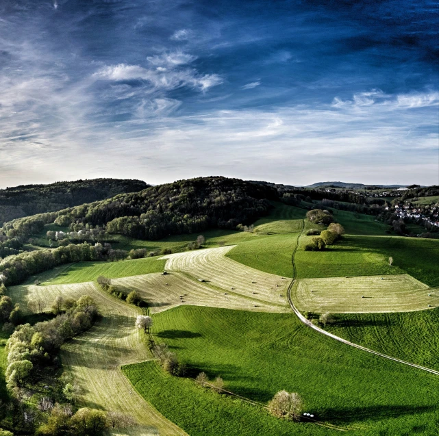 a wide expanse of grass and farmland on the side of a mountain