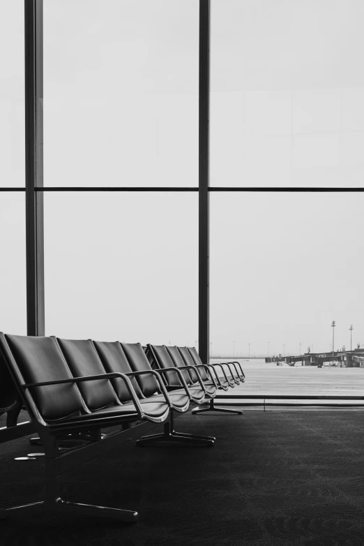 empty chairs sitting by a glass fence at an airport