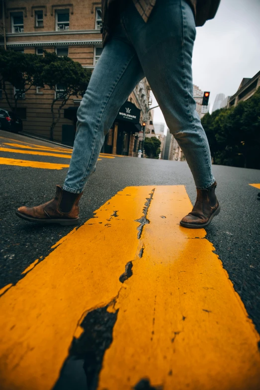 someone crossing the street in jeans and booties