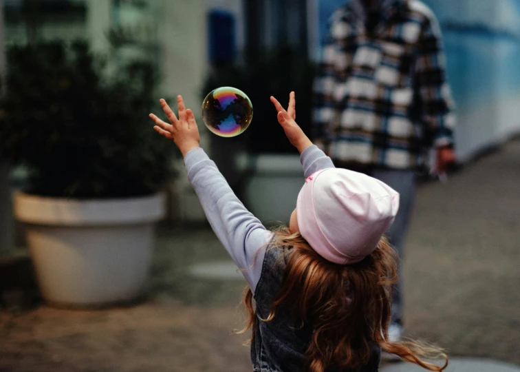 a girl wearing a hat is holding a bubbles ball