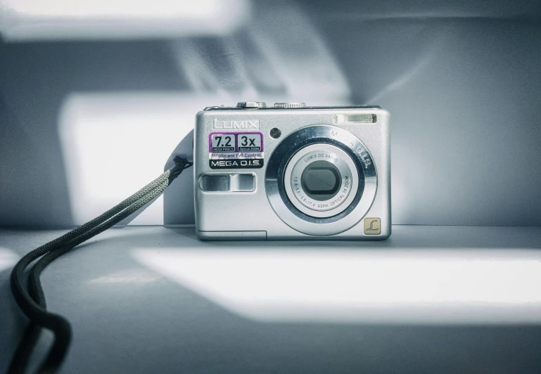 a silver digital camera with its strap attached