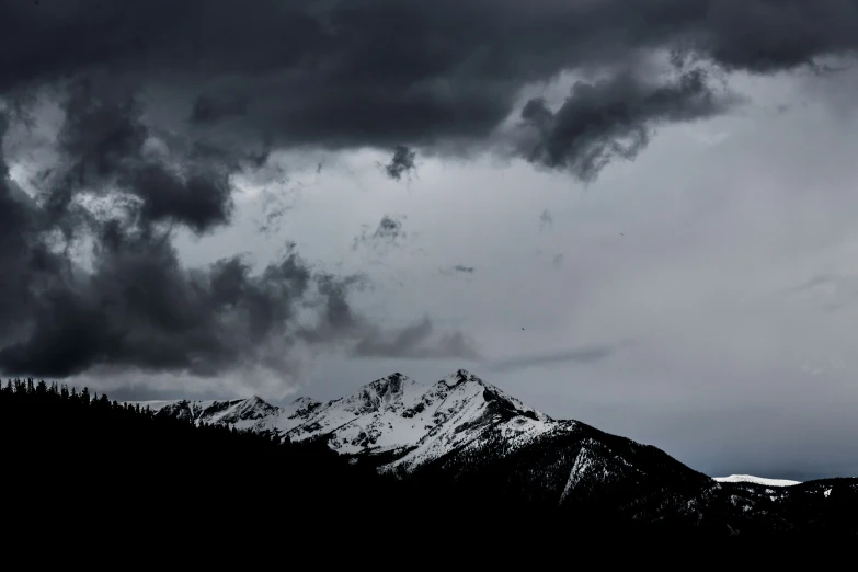 the sky is covered in dark clouds as the airplane flies overhead