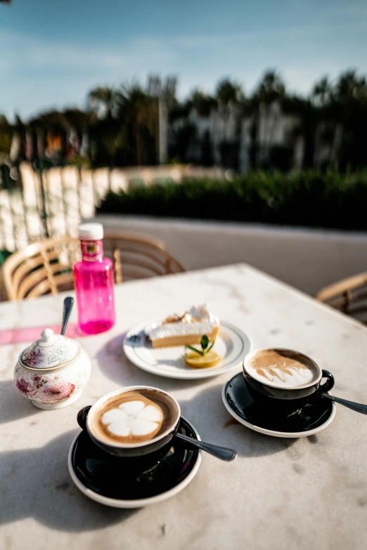 two cups of coffee and dessert on an outdoor table