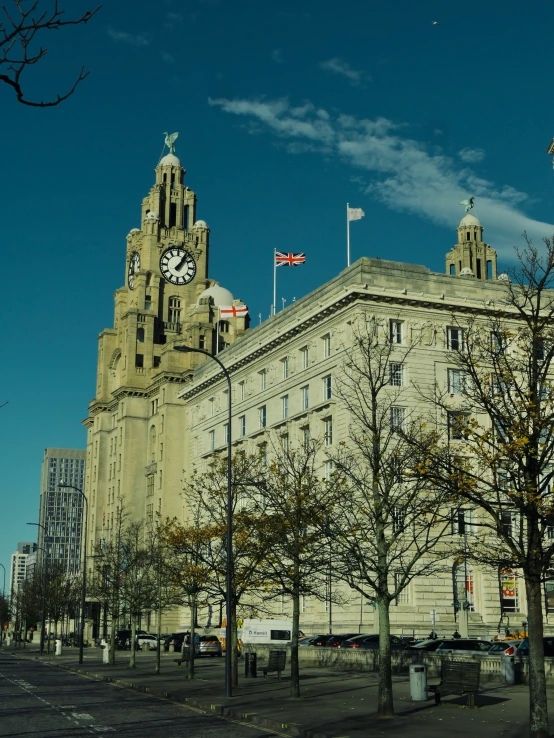 two tall buildings with flags flying in the air near trees