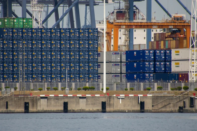 a tugboat floats past a dock with many containers in the background