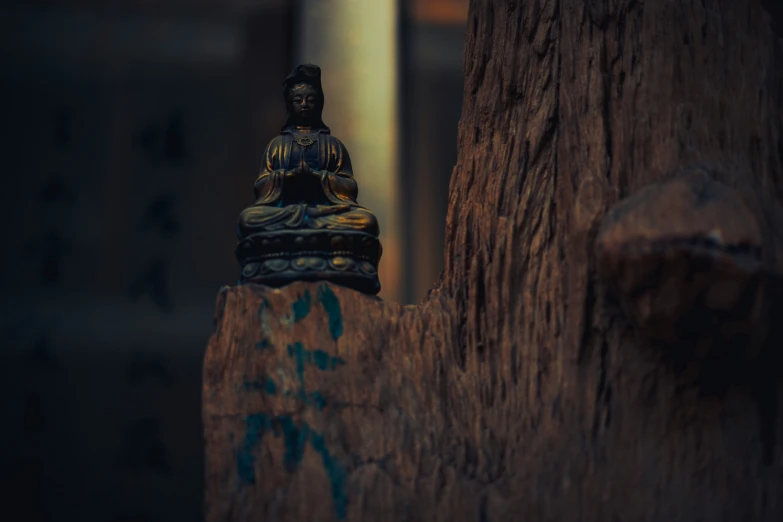 a small buddha sitting on top of a wooden statue