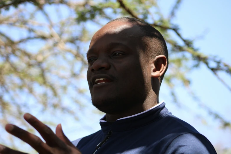 a man holding his hand out near a tree