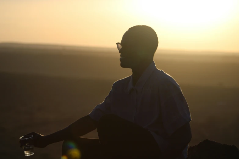 a man sitting on a rock as the sun rises